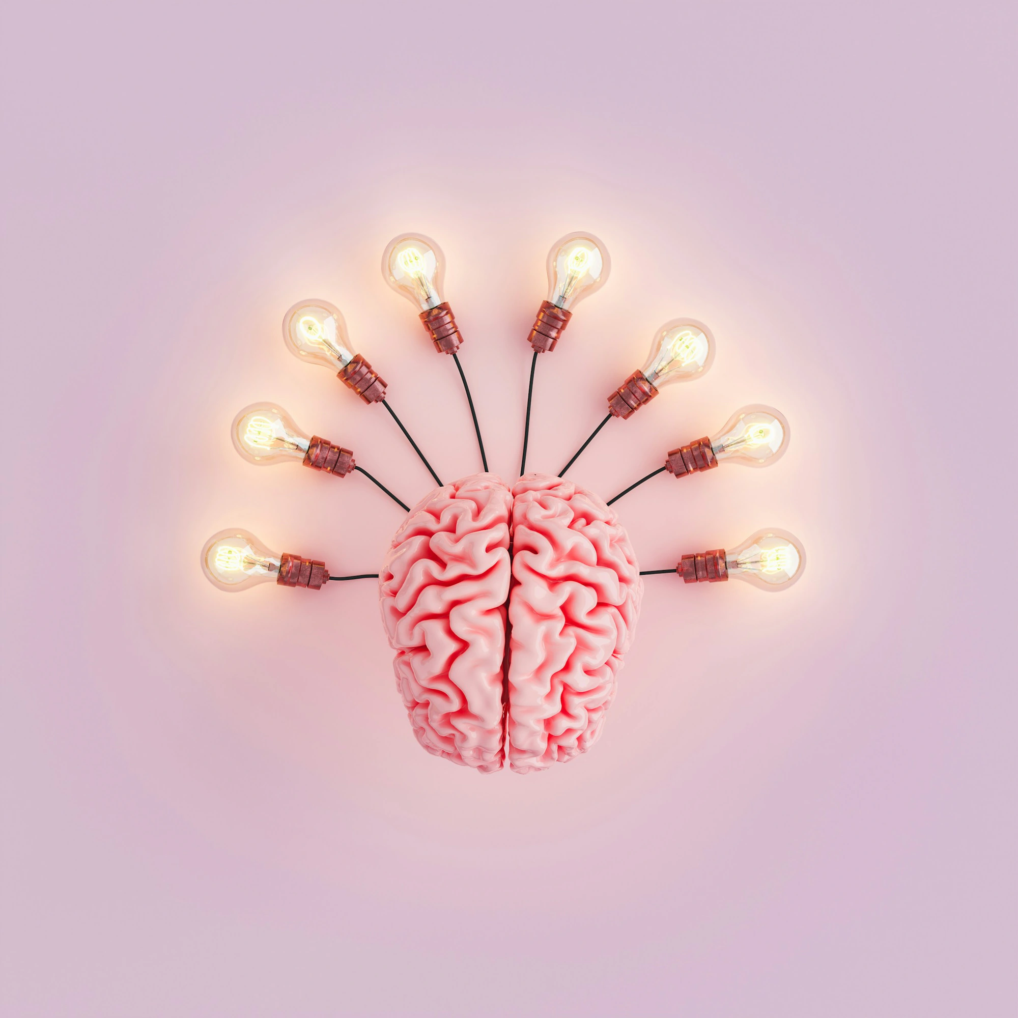 A pink brain model surrounded by glowing light bulbs against a pale pink background