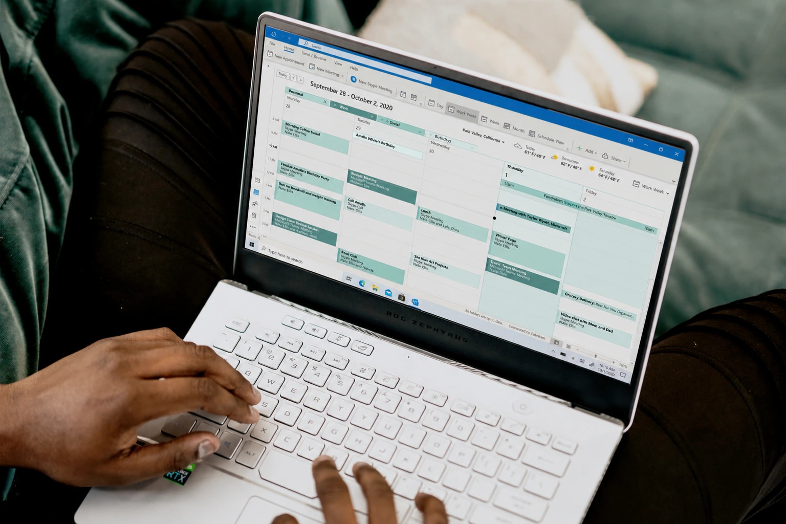 A person using a laptop displaying green and mint calendar blocks on a green sofa