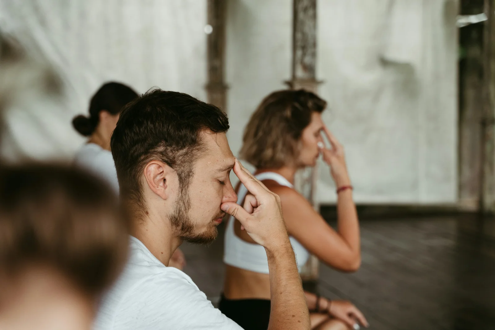 People seated during a breathing practice, holding one nostril closed
